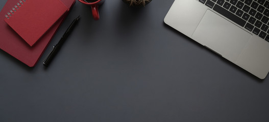 Top view of dark modern workplace with laptop computer, office supplies and red notebook with copy space