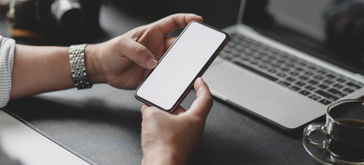 Cropped shot of businessman holding blank screen smartphone while working on his project