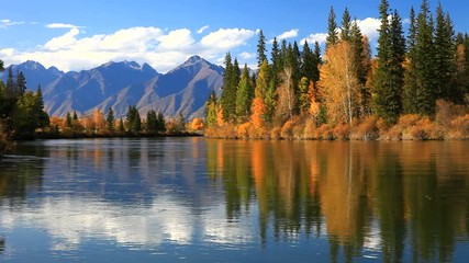 tranquil autumn landscape with a reflection of yellowed trees and a mountain range in the irkut rive
