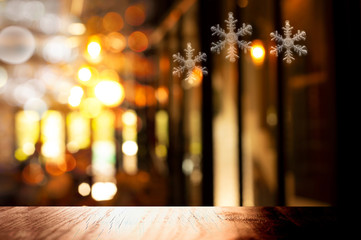 top of black wood table with christmas snowflake symbol in light of pub or bar party dark night back