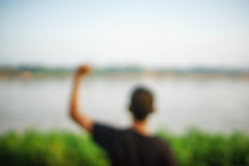 boy raise left hand in front of the river blur background