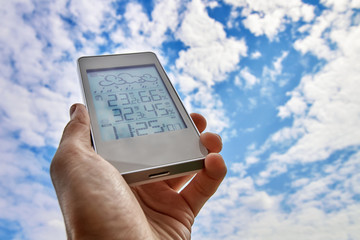 Wall Mural - Best personal weather station device with weather conditions inside and outside. A man holds a gadget in his hand on a background of sky and clouds