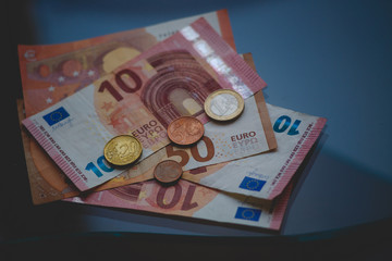 A few Euro bills and coins lie on a glass table.