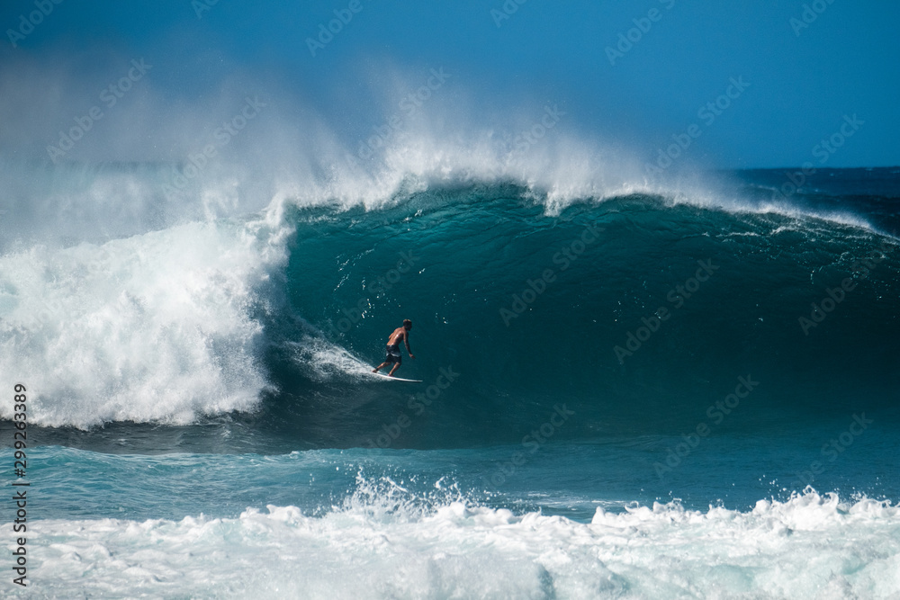 Surfer rides giant wave at the famous Banzai Pipeline surf spot located on the North Shore of Oahu in Hawaii - obrazy, fototapety, plakaty 