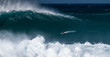 Surfer paddles and going to ride the giant wave at the famous Banzai Pipeline surf spot located on the North Shore of Oahu in Hawaii