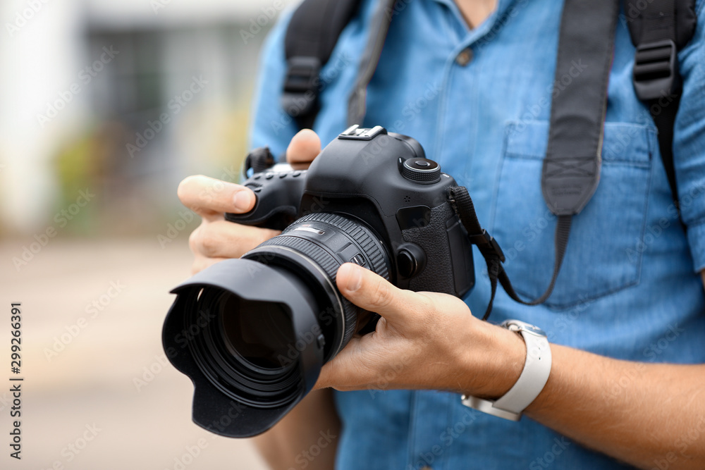 Young male photographer with camera outdoors, closeup - obrazy, fototapety, plakaty 