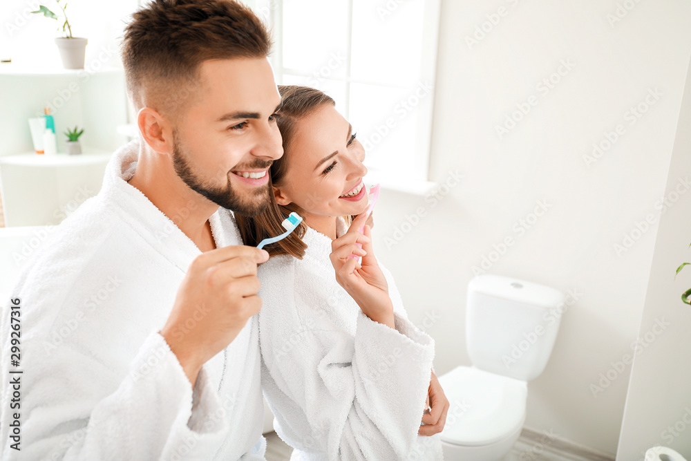 Young couple brushing teeth in bathroom - obrazy, fototapety, plakaty 