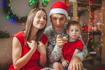 Wall Mural - Mom and dad give their son a gift in a red box. A young family with a child celebrates Christmas and New year at home