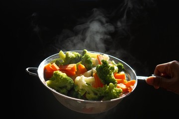 Wall Mural - steaming of hot boiled vegetables. Basket of vegetables that just boiled from hot water with steam selective focus, soft focus. hot food, diet and healthy concept.