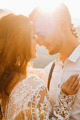 Stylish groom kissing gorgeous bride in sun light, perfect moment, boho wedding couple