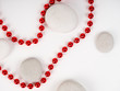© byallasaa - white sea stones and red beads between them on a white background. substrate, texture, red beautiful bright beads, beauty and style