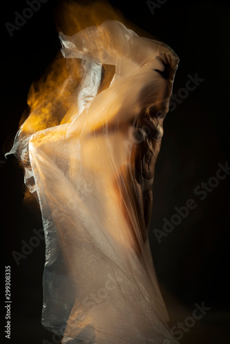 Fotomural Body of a beautiful girl gracefully fits a cellophane film fluttering in the wind