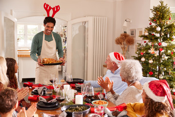 Multi-Generation Family Congratulating Father For Cooking Christmas Meal At Home