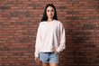 © New Africa - Portrait of young woman in sweater at brick wall. Mock up for design