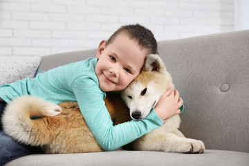 Wall Mural - Happy boy with Akita Inu dog on sofa. Little friends