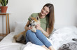 © New Africa - Young woman and Akita Inu dog in bedroom decorated with houseplants