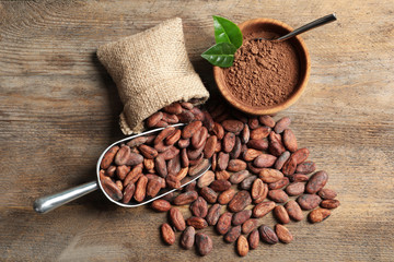 Flat lay composition with cocoa beans and powder on wooden table