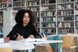 © New Africa - Young African-American woman studying at table in library