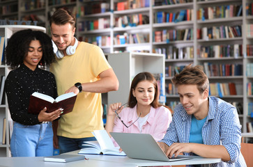 Wall Mural - Group of young people studying at table in library