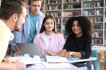 Wall Mural - Group of young people studying at table in library