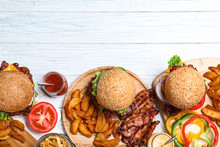 Flat Lay Composition With Fresh Bacon Burgers And Fries On White Wooden Table. Space For Text