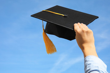 Wall Mural - Student with graduation hat and blue sky on background, closeup