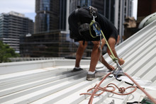 Construction Worker Wearing Safety Harness Using Secondary Safety Device Connecting Into 10.5 Mm Static Rope Using As Fall Restraint Repairing Roof Leak Working Positioning On Top Of The Roof   