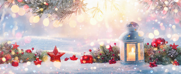 christmas lantern on snow with fir branch in the sunlight