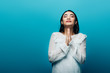 © LIGHTFIELD STUDIOS - brunette asian woman with closed eyes and praying hands on blue background