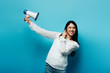 © LIGHTFIELD STUDIOS - brunette asian woman holding loudspeaker on blue background