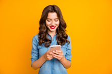 Photo Of Cheerful Cute Girl Looking For New Information Through Social Media Smiling Toothily Holding Telephone Isolated Over Yellow Vivid Blue Background
