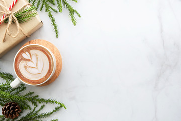 White marble table with cup of latte coffee and Christmas decoration with gift box. Christmas and new year celebration concept. Top view with copy space, flat lay.