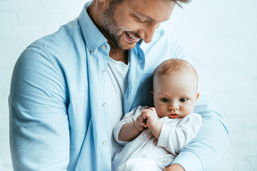 Wall Mural - happy father smiling while holding adorable little daughter