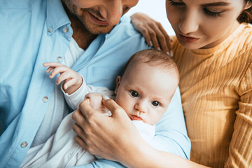 Wall Mural - cropped view of happy husband and wife holding little child