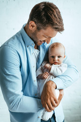 Wall Mural - happy father smiling while holding cute little daughter