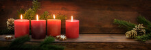 Fourth  Sunday In Advent, Four Burning Red Candles In A Row, Fir Branches And Christmas Decoration On Dark Rustic Wood, Wide Panoramic Format With Copy Space