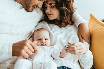 Wall Mural - cropped view of man hugging beautiful wife holding little daughter