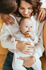 Wall Mural - cropped view of man looking at adorable baby holding Christmas ball while sitting on mothers hands