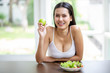 © iammotos - happy sexy young asian woman in white singlet smiling , holding green apple and eating fresh organic salad . A beautiful girl have breakfast healthy good food in morning at home. weight loss concept.