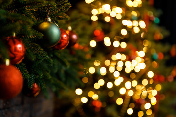 Christmas and New Year interior - blur background: fireplace, lamps, green Christmas tree, brown leather sofa, gifts, candles, moose rocking chair.  Lots of lights glowing in the dark.