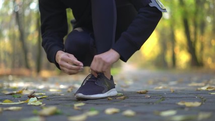 Wall Mural - Autumn running woman tie shoes in park