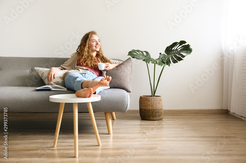 Cuadros en Lienzo Curly haired brunette woman relaxing on the couch at home.