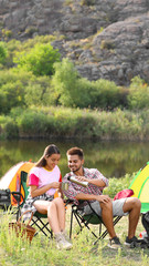 Sticker - Young couple with hot drinks  resting outdoors. Camping vacation