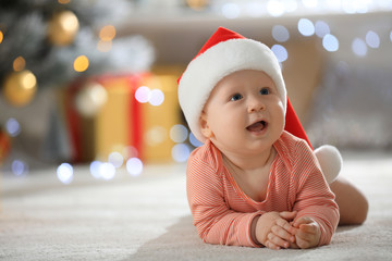 Wall Mural - Little baby wearing Santa hat on floor indoors. First Christmas