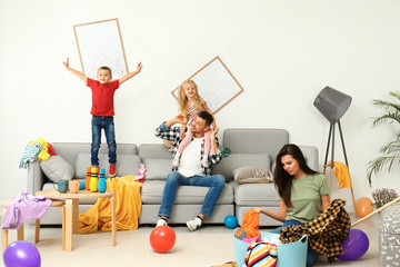 Wall Mural - Frustrated mother trying to clean up mess while father playing with children in room