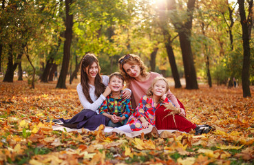 Portrait of happy family in forest park in autumn colorful landscape, motherhood and carefree childhood in nature outdoors