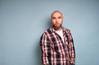 © bestsenny - A guy with a beard in a plaid shirt stands on a blue background, looks at the camera and shows his tongue in displeasure.