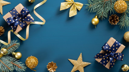 christmas border frame of fir tree branches and golden decorations around blue background with copy 