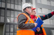 © silentalex88 - An engineer with a hard hat and helmet discussing a project at a construction site with a team leader in autumn or winter. architecture construction concept. Industrial safety