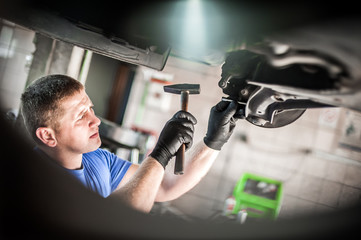 Wall Mural - Auto mechanic repairer checking condition under car on vehicle lift